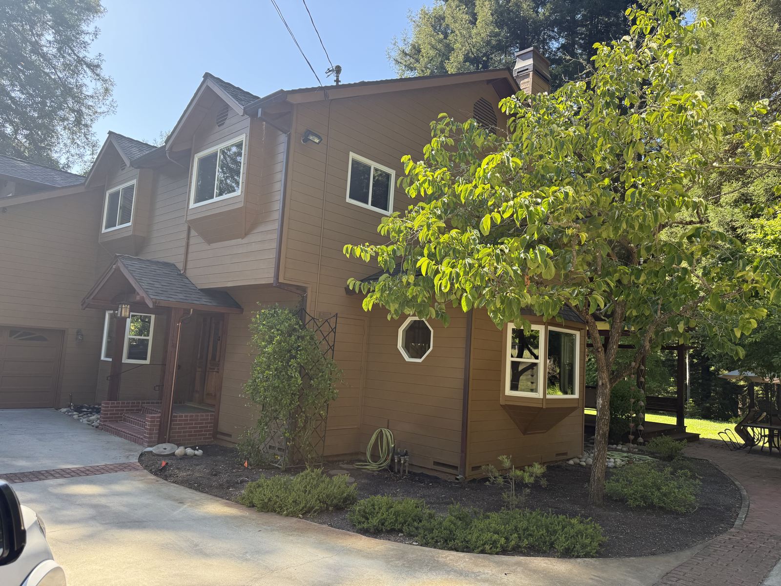 Two-story wood-sided home among redwoods with gable vents and foundation vents visible