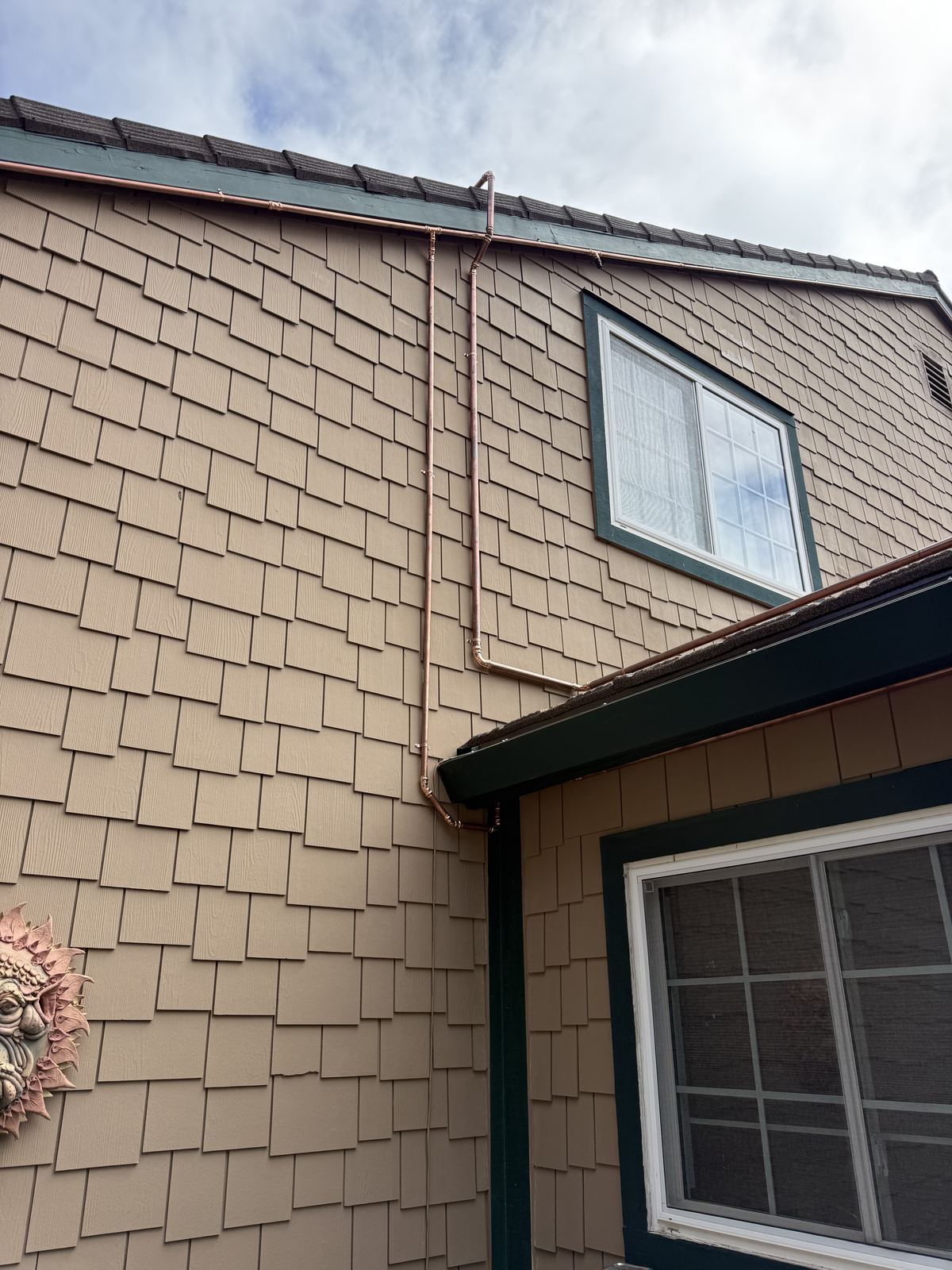 Copper exterior sprinkler lines running along the eaves of a fiber cement shake home