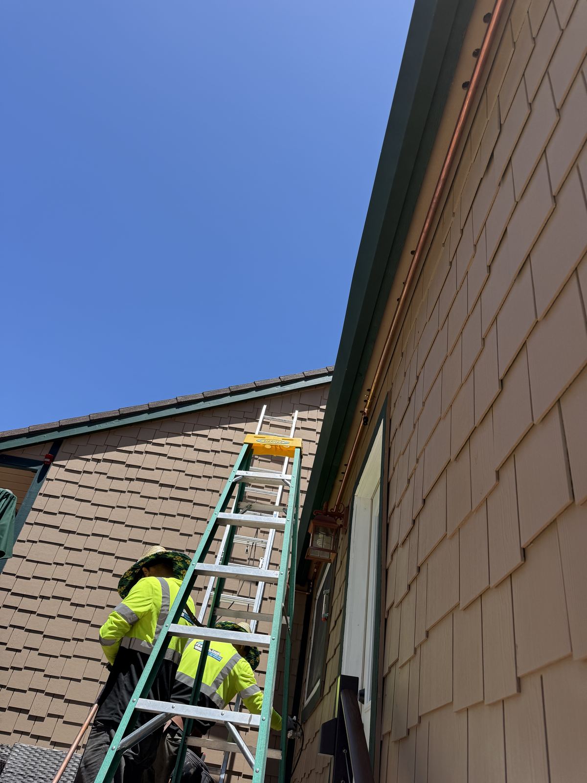 A crew installs hardening upgrades along an eave line